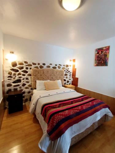 a bedroom with a bed and a stone wall at Hotel Humantay lodge Ollantaytambo in Ollantaytambo