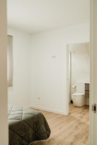 a white bedroom with a bed and a toilet at Villa alegre in Elche