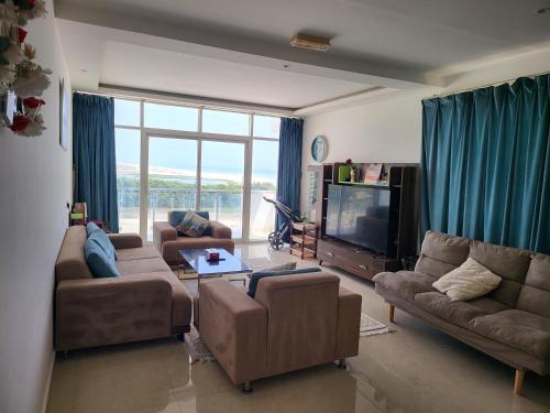 un soggiorno con divani e TV a schermo piatto di SeaViewApartment a Salalah
