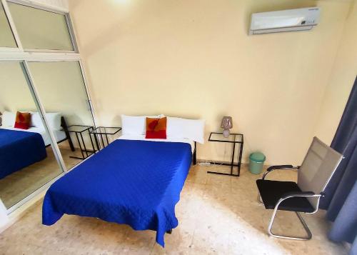 een slaapkamer met een blauw bed en een stoel bij Refugio Encantador in Santo Domingo