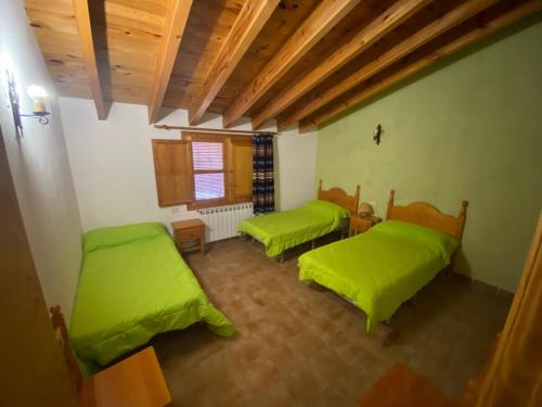 una camera con due letti con lenzuola verdi di Casa Alta 14 B a Palanques