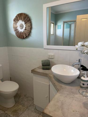 a bathroom with a sink and a toilet and a mirror at Beach Road Bliss- Whitsundays in Cannonvale