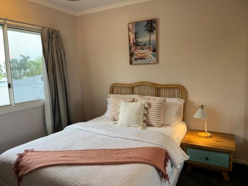 a bedroom with a bed with white sheets and a window at Beach Road Bliss- Whitsundays in Cannonvale