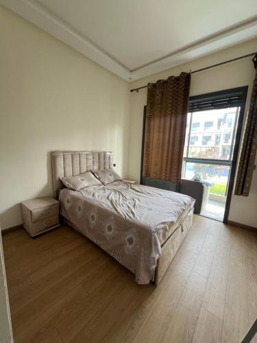 a bedroom with a bed and a large window at Appartement tamaris les crêtes in Casablanca