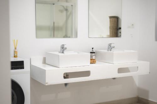 een witte badkamer met 2 wastafels en een wasmachine bij New - MiJa basement Loft Apartment steps from Beach - perfect for Sun and Sport Seekers in Marbella