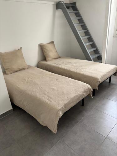twee bedden naast een trap in een kamer bij Chez Aurore in Port-de-Bouc