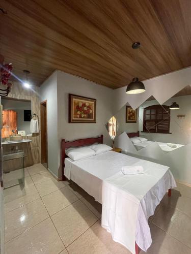 a bedroom with a large bed and a bathroom at Pousada Hibiscos in Serra do Cipo