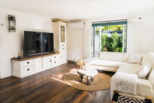 a living room with a white couch and a tv at Boshuisje de Kastanje - Chalet met prive hottub in Putten
