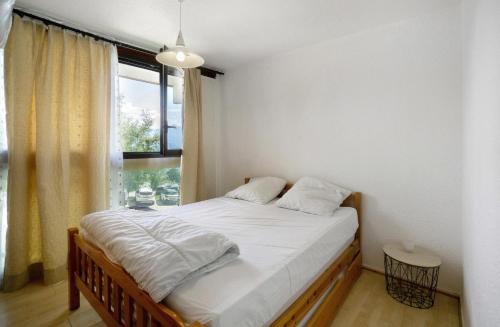 a bedroom with a bed with white sheets and a window at Au pied des pistes (Le Corbier/73) in Villarembert