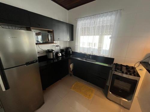 a kitchen with a stainless steel refrigerator and a sink at Casa de Temporada, 2 Quartos com Ar - Prado BA in Prado