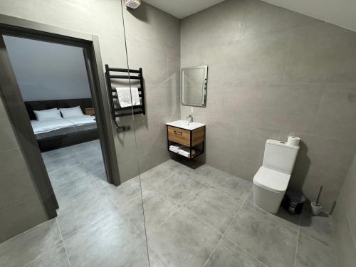 a bathroom with a toilet and a sink and a bed at cottages GRUN in Yablunytsya