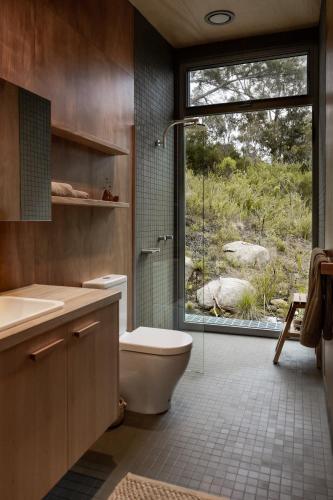 a bathroom with a shower and a toilet and a window at Swansong - Experience simple environmental living in St Helens