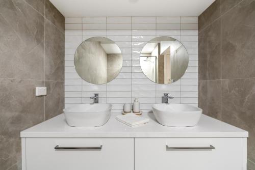 a bathroom with two sinks and two mirrors at The Ocean Gem at Rosebud with its own Private Beach Box in Rosebud