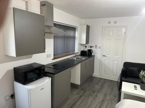 a small kitchen with a sink and a microwave at Lodge by Oak in West Bromwich