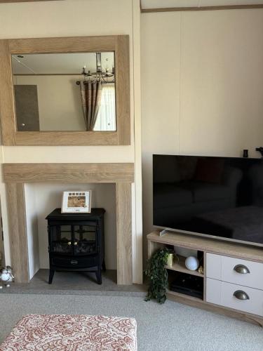 een woonkamer met een televisie en een spiegel bij Bishops Beach Stays in Walton-on-the-Naze