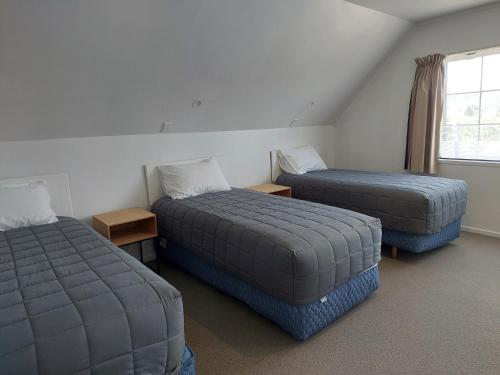 a bedroom with two beds and a window at Camellia Court Motel in Lower Hutt