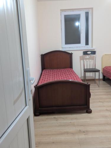 een bed in een kamer met een raam en een stoel bij Cozy Home in Balaovit