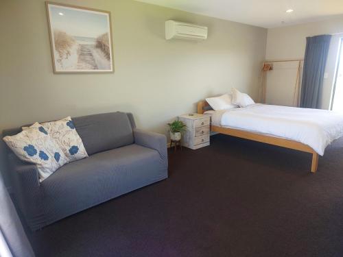 a small bedroom with a bed and a couch at Mapua Hills Hideaway in Upper Moutere