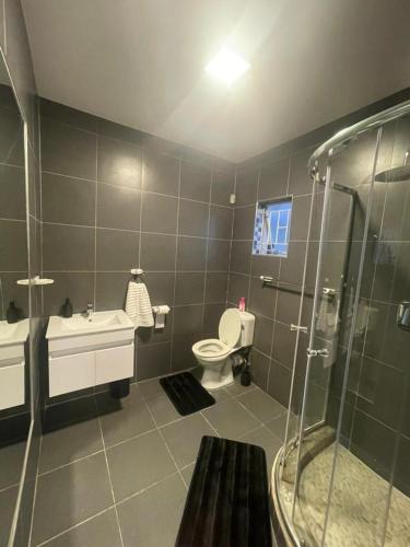 a bathroom with a shower and a toilet and a sink at Pine Self-Catering Unit in Windhoek
