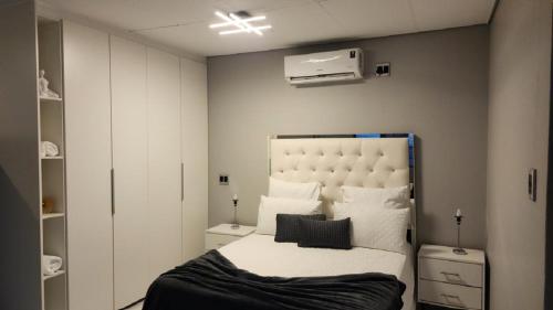 a bedroom with a large bed with white sheets and pillows at Pine Self-Catering Unit in Windhoek