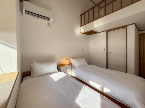 two beds in a small room with a window at KijimaBase - Base 1 in Kijimadaira