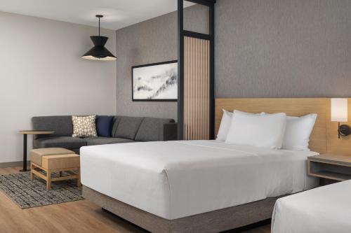 una camera da letto con un grande letto bianco e un divano di Hyatt Place Toronto Airport a Toronto