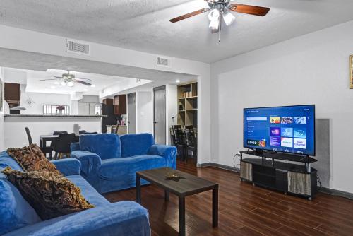 a living room with blue couches and a flat screen tv at 6 Bedroom house 15 minutes from iah airport. in Houston