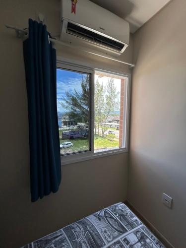 a bedroom with a window and a bed and a window with a view at Edificio Freitas in Imbituba