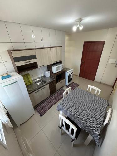 a small kitchen with a table and a refrigerator at Edificio Freitas in Imbituba