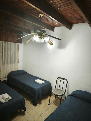 a room with two beds and a ceiling fan at Hostería Michel in Villa Gesell