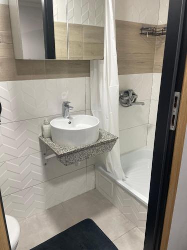 une salle de bain blanche avec un lavabo et une baignoire dans l'établissement Apartament Norwida przy Parku, à Jelenia Góra