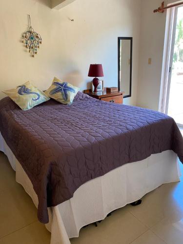 a bedroom with a bed with a purple comforter at Condo Riviera in Puerto Aventuras