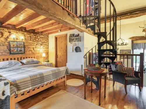 a bedroom with a bed and a spiral staircase at The Cowshed in Penrith