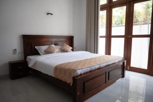 a bedroom with a bed and a large window at Ashasha Villa in Negombo