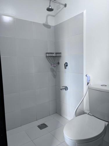 a white bathroom with a toilet and a shower at Cozy Nook in the City in Manila