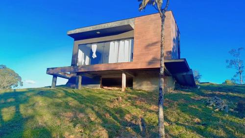 a house on top of a hill with a tree at Chalés Refúgio nas montanhas in Guaratuba