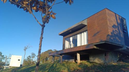 a house on top of a hill with a tree at Chalés Refúgio nas montanhas in Guaratuba