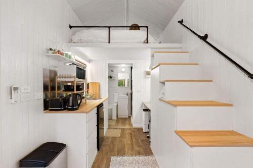 een kleine kamer met witte muren en een trap en een keuken bij Celestial Haven by Tiny Away in Toolangi