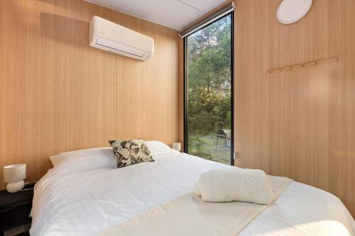 a bedroom with a white bed and a window at Quantum Field by Tiny Away in Toolangi