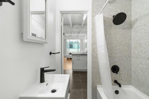 a white bathroom with a sink and a bath tub at Métropolitain Le Cachet in Quebec City
