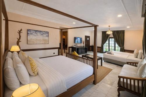 une chambre avec un grand lit et un salon dans l'établissement Frangipani Langkawi Resort, à Pantai Cenang