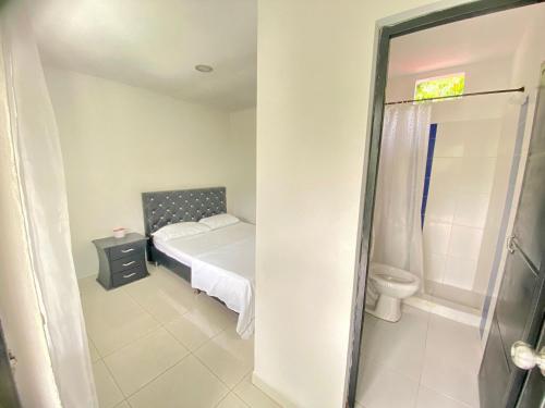 a small bedroom with a bed and a toilet at Finca Tres Potrillos Villeta in Villeta