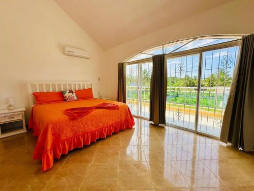 a bedroom with an orange bed and a large window at Villa Tropical Cabarete in Sosua