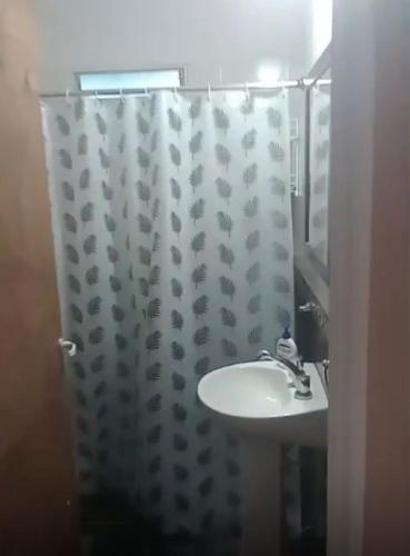 a bathroom with a sink and a shower curtain at El Tito Alojamiento in San Roque