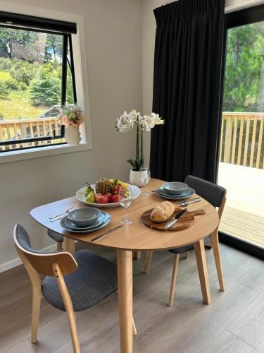 a wooden table with a bowl of fruit on it at Kauri Cabins Tranquil Retreat in Whitianga