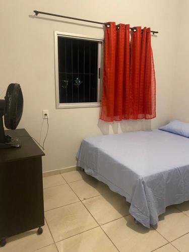 a bedroom with a bed and a window with red curtains at Casa completa com dois quartos e estacionamento grátis in Serra