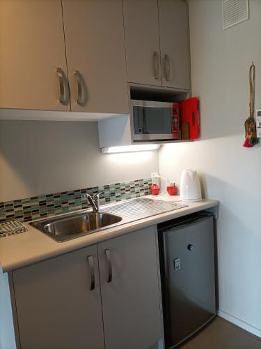 a kitchen with a sink and a microwave at Central Diamond Harbour Guest Suite in Diamond Harbour