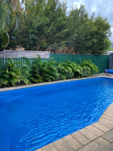 una piscina blu con recinzione e alberi di 2 Long between breaks a Coffs Harbour