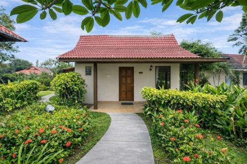 een klein huisje met een rood dak bij Frangipani Langkawi Resort in Pantai Cenang