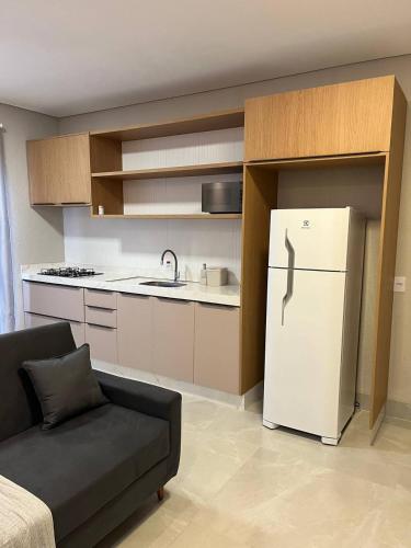a kitchen with a white refrigerator and a couch at Atalaia Apart in Sinop